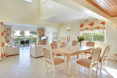a dining room and living room with a table and chairs at Villa Adele in Albufeira
