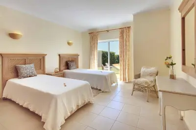 a bedroom with two beds and a table and a window at Villa Adele in Albufeira