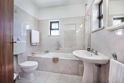 a white bathroom with a tub and a toilet and a sink at Villa Severino in Albufeira