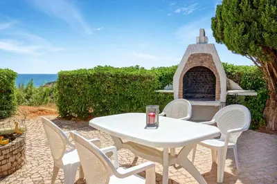 a white table and chairs on a patio with a fireplace at Villa Coelha in Albufeira