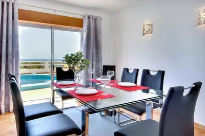 a dining room with a table and chairs and a window at Villa Coelha in Albufeira