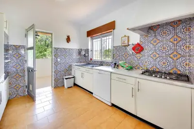 a kitchen with white cabinets and a tile wall at Villa Coelha in Albufeira