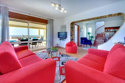 a living room with red furniture and a view of the ocean at Villa Coelha in Albufeira