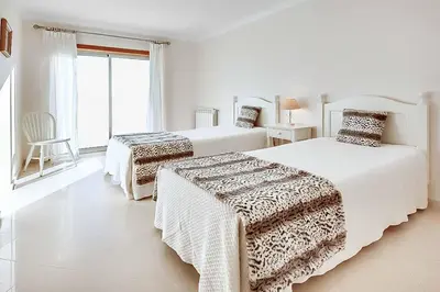 a white bedroom with two beds and a window at Casa Ferrero in Guia