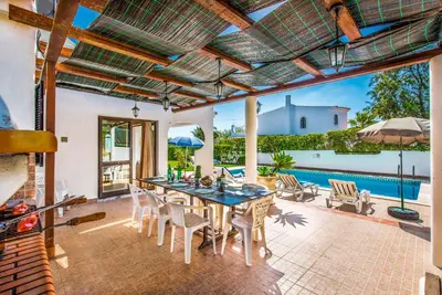 an outdoor patio with a table and chairs and a pool at Villa Miramar in Albufeira