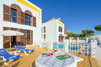 a patio with a table and chairs and a pool at Villa Albuar in Albufeira