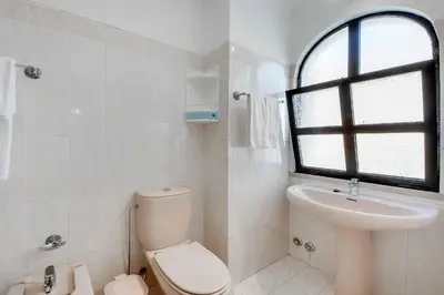 a white bathroom with a toilet and a sink at Villa Albuar in Albufeira