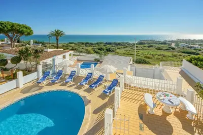 a swimming pool with lounge chairs and the ocean at Villa Albuar in Albufeira
