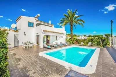 a villa with a swimming pool in front of a house at Casa dos Amigos in Albufeira