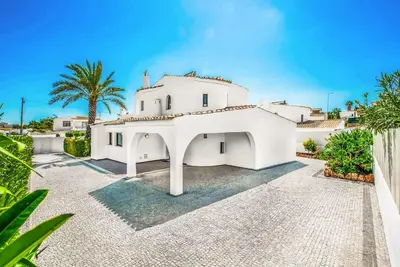 a white house with a palm tree at Casa dos Amigos in Albufeira