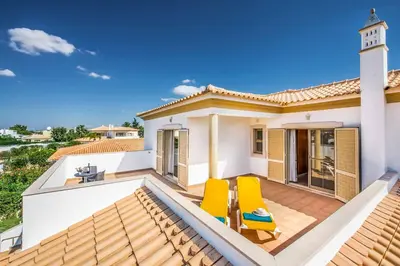 a patio with two yellow chairs and a house at Villa Altair in Albufeira