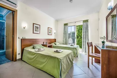 a hotel room with two beds and a desk and window at Villa Altair in Albufeira