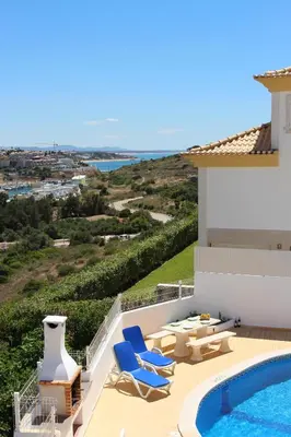 a villa with a swimming pool and blue lounge chairs at Villa Sunny in Albufeira
