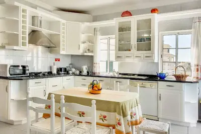a kitchen with white cabinets and a table with fruit on it at Villa Sunny in Albufeira