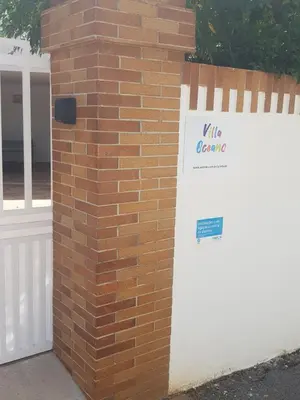 a brick wall with a white gate with a sign on it at Villa Oceano in Albufeira