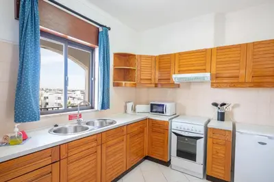 a kitchen with wooden cabinets and a sink and a window at Apartamentos Old Town by Umbral in Albufeira