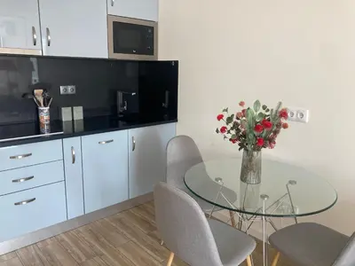 a kitchen with a glass table with chairs and a vase of flowers at CASA JOY Vilamoura apartment in Vilamoura
