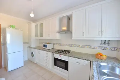 a kitchen with white cabinets and a white refrigerator at TownHouse next to Falésia Beach in Albufeira