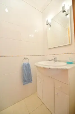 a white bathroom with a sink and a mirror at TownHouse next to Falésia Beach in Albufeira