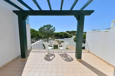 a pergola with two chairs on a balcony at TownHouse next to Falésia Beach in Albufeira
