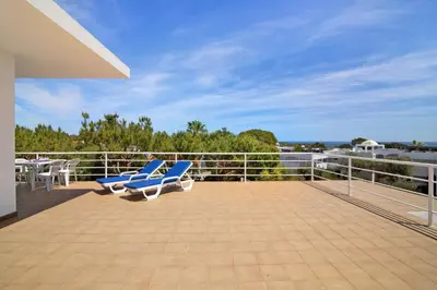 a balcony with two blue chairs and a table at Yara Beach Apartments with Terrace in Albufeira