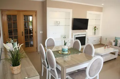 a dining room with a table and chairs and a tv at Rising Sun Apartment in Albufeira