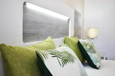 a room with green pillows on a bed with a window at Rising Sun Apartment in Albufeira