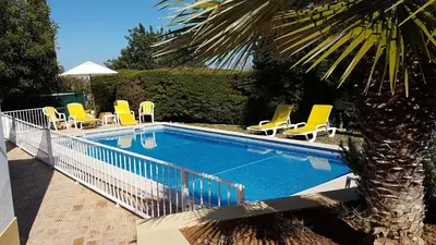 a swimming pool with yellow chairs and a palm tree at Casa Dos Cedros in Guia