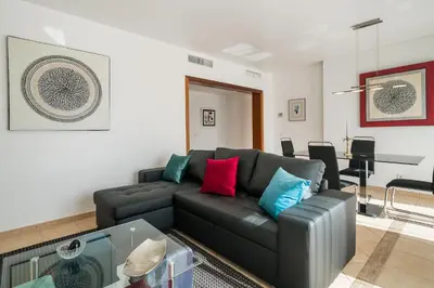 a living room with a black couch with colorful pillows at Vilasol apartment by Intiholidays in Vilamoura