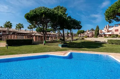 a blue swimming pool in a yard with trees at Vilasol apartment by Intiholidays in Vilamoura