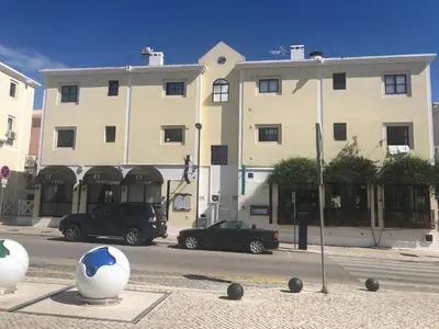 a black car parked in front of a large building at Vilamoura 2 bed new apartment in Vilamoura