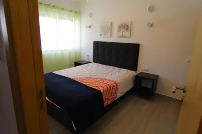 a bedroom with a bed with a black headboard and a window at Apartamento das Oliveiras in Albufeira