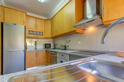 a kitchen with wooden cabinets and a stainless steel sink at Pinheiros da Balaia Villas in Albufeira