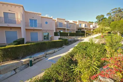 a row of houses on a street with bushes at Pinheiros da Balaia Villas in Albufeira