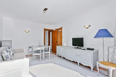 a white living room with a tv and a couch at AZUL/MAR ALBUFEIRA 602 in Albufeira