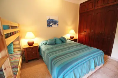 a bedroom with a bed with blue pillows on it at Apt T2 Jardins do Castelo - Albufeira, Algarve in Albufeira
