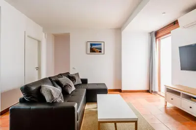 a living room with a black leather couch and a tv at Aldeia das Açoteias Apartment in Roja- Pé