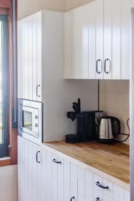 a kitchen with white cabinets and a microwave at Aldeia das Açoteias Apartment in Roja- Pé