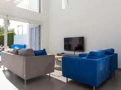 a living room with two blue couches and a tv at Harmony 4F House - Privat Heated Pool & Privacy & Albufeira in Albufeira