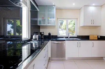 a kitchen with white cabinets and black counter tops at Villa Carlivo in Albufeira