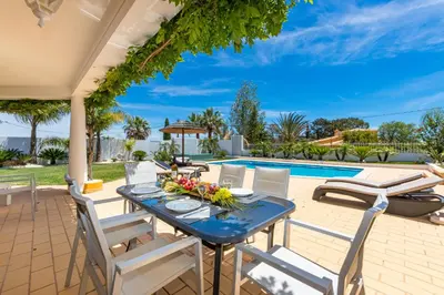 a patio with a table and chairs and a pool at Villa Casinha in Albufeira
