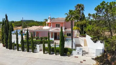 a pink house with trees in front of it at Villa Duma in Albufeira