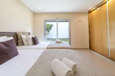 a bedroom with two beds and a large window at Villa Maria in Albufeira