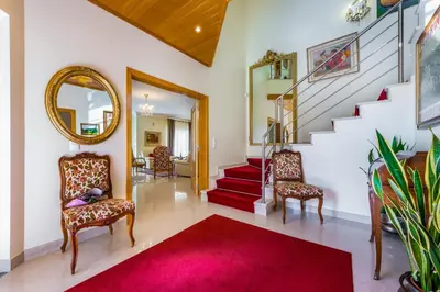 a living room with stairs and chairs and a red rug at Villa Cor de Rosa in Albufeira