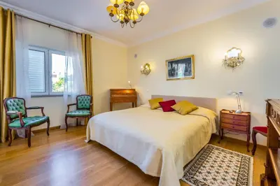 a bedroom with a bed and two chairs and a chandelier at Villa Cor de Rosa in Albufeira