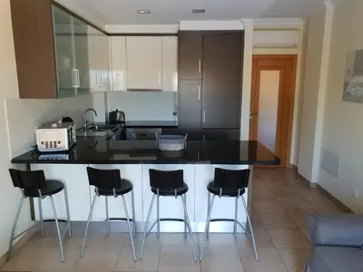 a kitchen with a black counter and black stools at Quinta do Pinheiro Residence in Albufeira