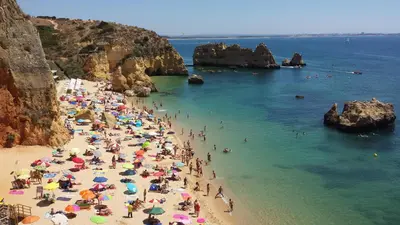 a crowd of people on a beach with umbrellas at Quinta do Pinheiro Residence in Albufeira