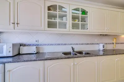 a kitchen with white cabinets and a sink at Rei - Quarteira - 3 min to the beach in Vilamoura