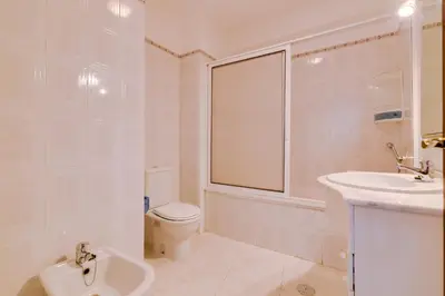 a white bathroom with a toilet and a sink at Rei - Quarteira - 3 min to the beach in Vilamoura