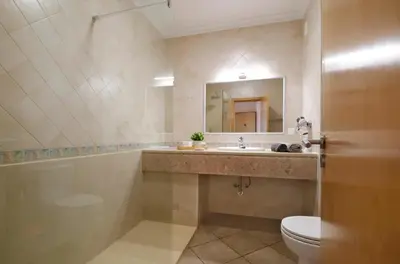 a bathroom with a sink and a toilet and a mirror at Apt Baleeira Sol in Albufeira